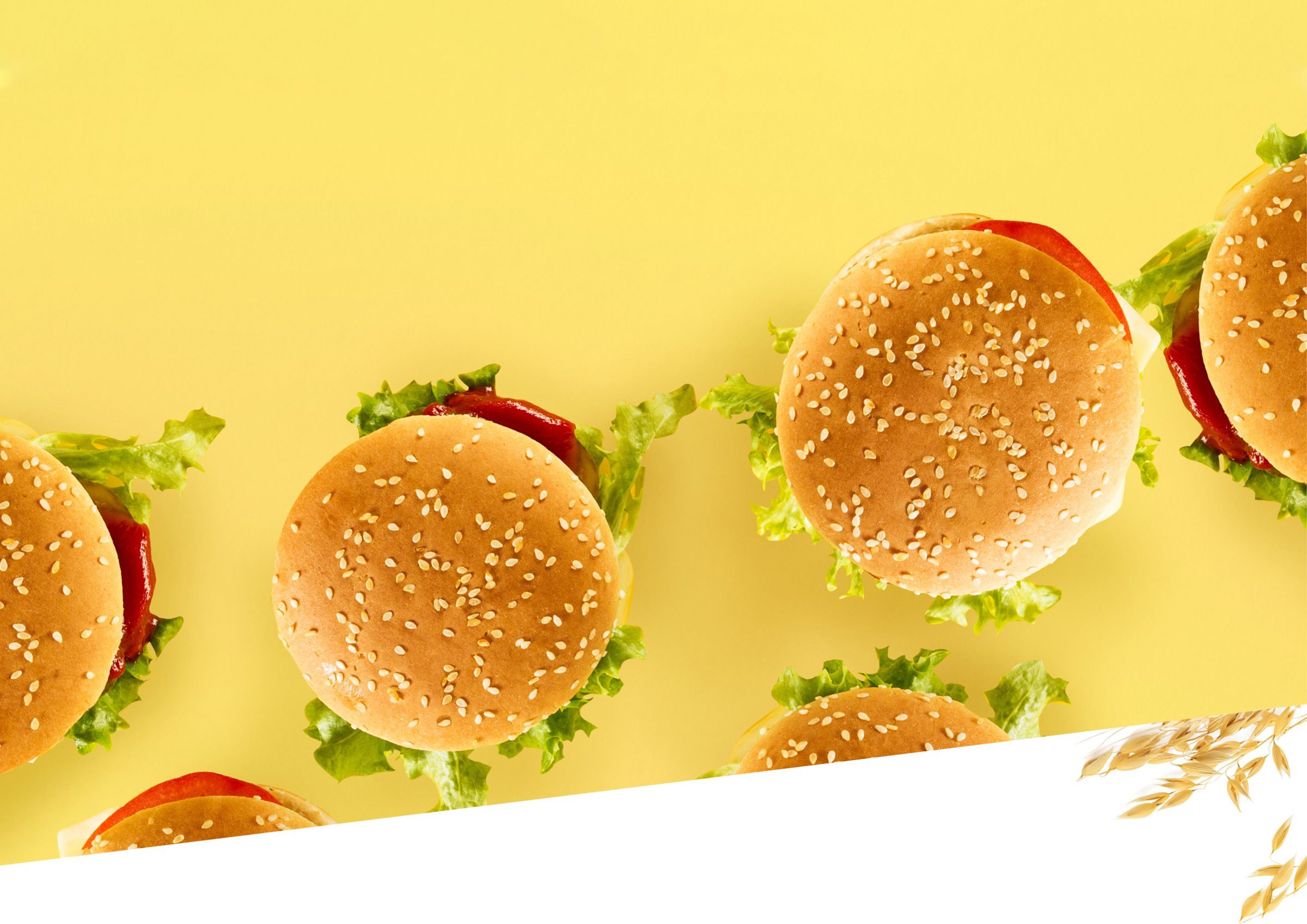 Burgers with sesame seed buns on yellow surface.